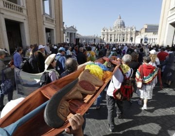 Saturday, Oct. 19, 2019, members of Amazon indigenous populations walk during a Via Crucis (Way of the Cross) procession from St. Angelo Castle to the Vatican. In foreground is a wooden statue portraying a naked pregnant woman. (Andrew Medichini/AP Photo)