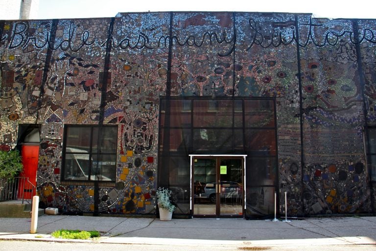 The Painted Bride Art Center is draped in black mesh since it was discovered that the Isaiah Zagar mural that covers it is separating from its walls. (Emma Lee/WHYY)