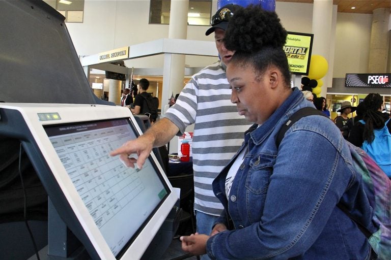 Community College of Philadelphia student Hanna Archibald, 20, learns how to use a new voting machine from Matthew McKeon of the City Commissioners Office. (Emma Lee/WHYY)