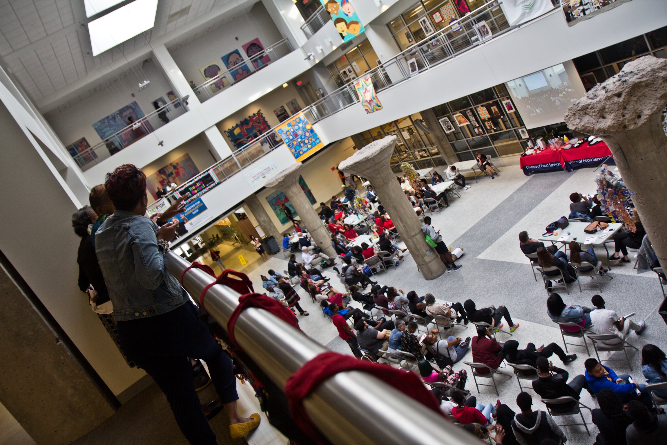 An overflow of parents and students gather around a packed meeting