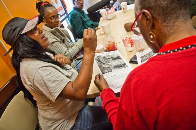 Sonya Sanders, (left), who lives near the Philadelphia Energy Solutions complex in South Philadelphia, reads the Chemical Safety Board's report on the refinery fire. (Kimberly Paynter/WHYY)