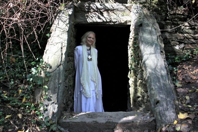 Kris Soffa, a trail ambassador for the Friends of the Wissahickon, stands in the entrance to the Cave of Kelpius, located on the trails near the southern end of the 1,800-acre Wissahickon Valley Park, a section of Fairmount Park in Northwest Philadelphia. . (Emma Lee/WHYY)