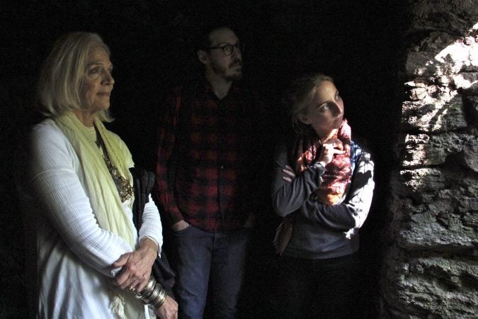 Kris Soffa, Shai Ben-Yaacov and Kelsey Hanson look out on the woods of the Wissahickon from the Cave of Kelpius. It is believed that Kelpius and his followers used the cave to store books and scientific equipment. (Emma Lee/WHYY