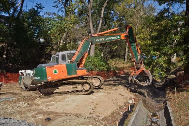 An excavator removes concrete pipe as part of a plan to restore a waterway at Conklin Recreation Center. (Kimberly Paynter/WHYY)