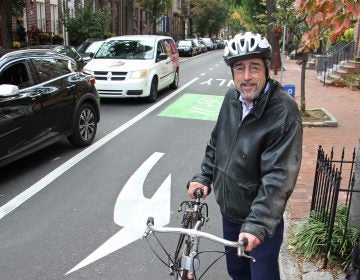 Larry Spector, president of the Society Hill Civic Association, hops off his bike at 5th and Pine streets. (Emma Lee/WHYY)