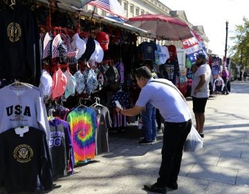 In this Oct. 15, 2019, photo a Chinese tourist takes pictures of Washington DC t-shirts at a tourism kiosk in Washington. (Bani Sapra/AP Photo)