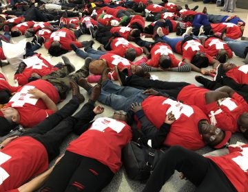 Food prep workers die-in at the Philadelphia airport on Wednesday night to demonstrate the life and death stakes of lacking affordable healthcare. (Nina Feldman/WHYY)