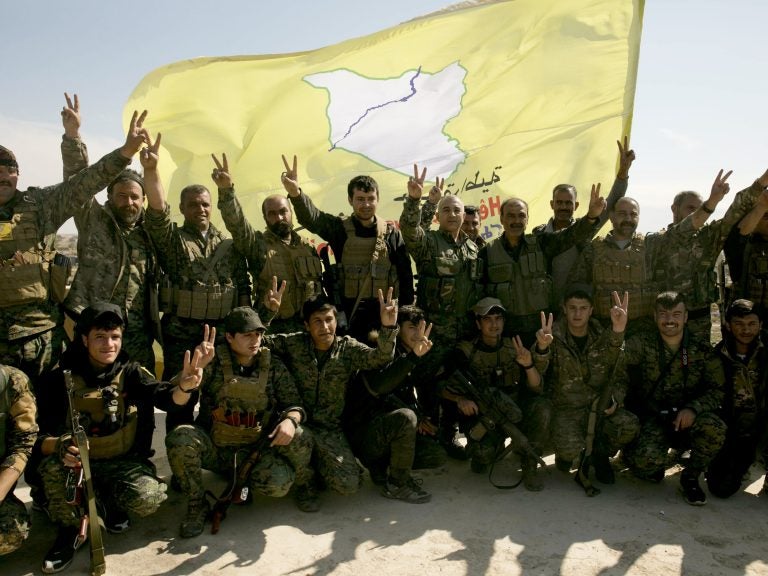 U.S.-backed Syrian Democratic Forces (SDF) fighters pose for a photo in Baghouz, Syria, after the SDF declared the area free of Islamic State militants, in March. (Maya Alleruzzo/AP)