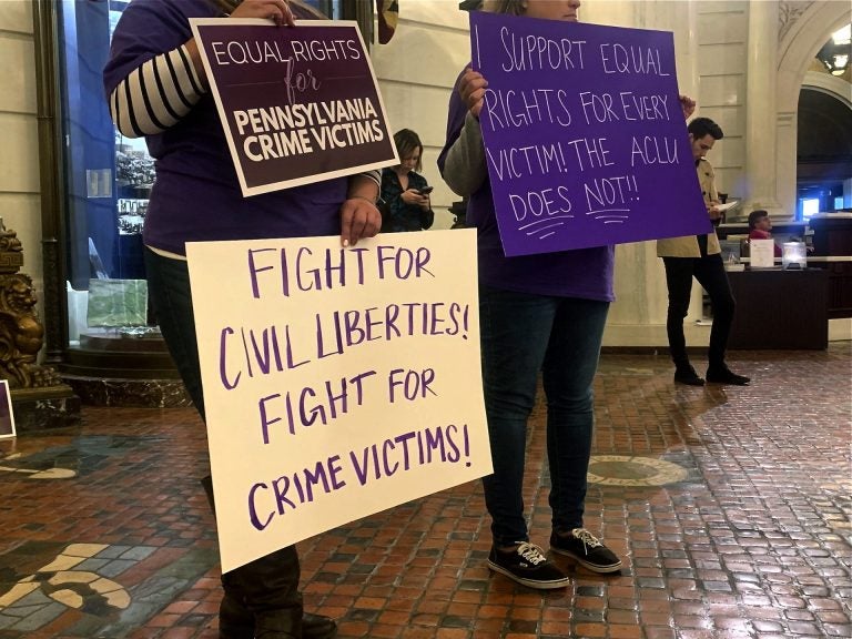 Supporters of Marsy's Law held signs in protest during the ACLU's press conference announcing its lawsuit. (Katie Meyer/WITF)
