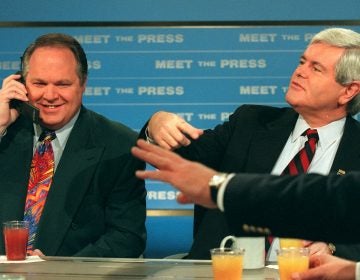 Radio talk show host Rush Limbaugh talks on a phone as House Speaker Newt Gingrich gestures during a break in taping of NBC's 