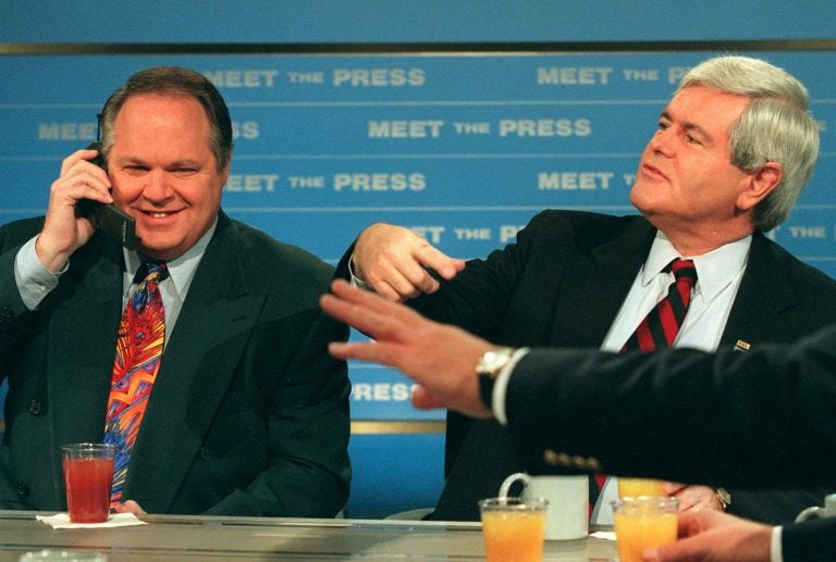 Radio talk show host Rush Limbaugh talks on a phone as House Speaker Newt Gingrich gestures during a break in taping of NBC's 