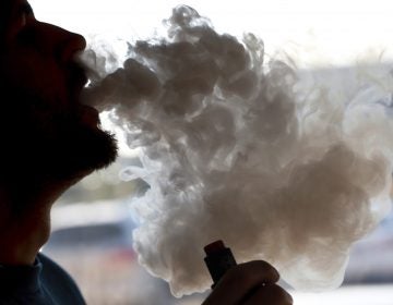 A man exhales a puff of smoke from a vape pipe