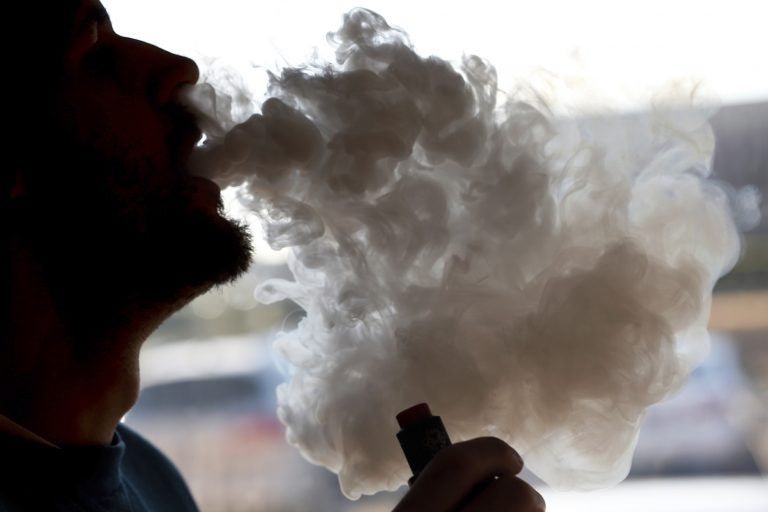 A man exhales a puff of smoke from a vape pipe