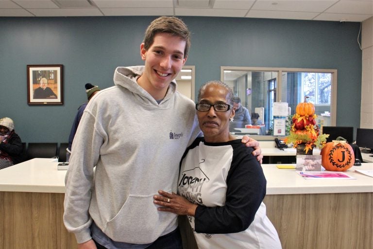 Rutgers-Camden student Nitan Shanas embraces Joseph's House client and volunteer Liz Holmes in the lobby of the Camden homeless shelter where they met. (Emma Lee/WHYY)