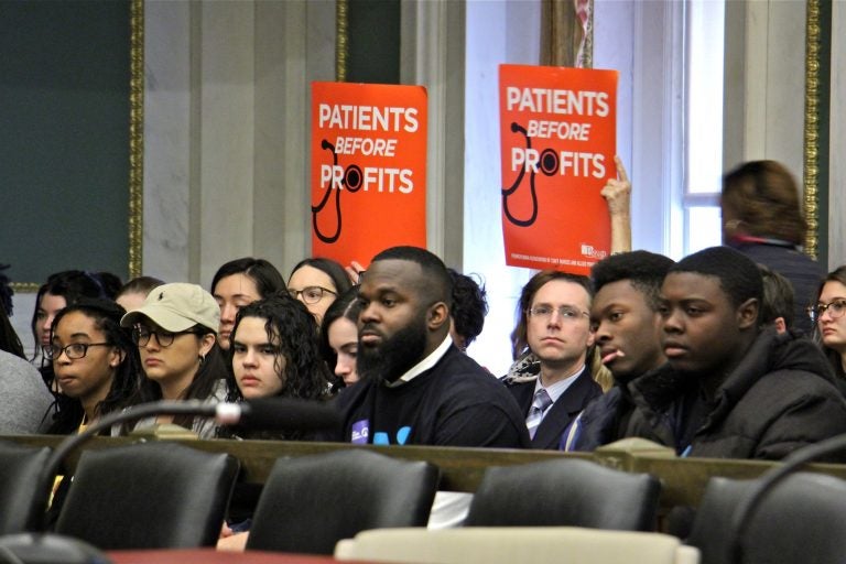 Supporters of a bill that woulf require hospitals to submit a closure plan before shutting down hold up signs during a hearing at City Hall. (Emma Lee/WHYY)