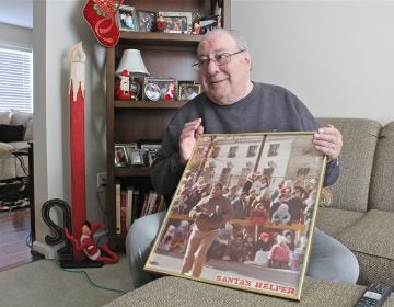 Robert DiBenedetto holds a photo of himself working Philadelphia's Thanksgiving Day Parade in the early 1980s. (Emma Lee/WHYY)
