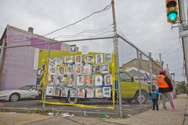Ros Pichardo, an activist with Operation Save Our City, hung the photos of other victims of gun violence across from the spot where 10 year-old Semaj O’Branty was shot in the head walking home from school Wednesday. (Kimberly Paynter/WHYY)