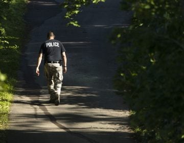An officer walks up a blocked off drive way, in, Solebury, Pa., as the search continues Wednesday, July 12, 2017, for four missing young Pennsylvania men feared to be the victims of foul play. (AP Photo/Matt Rourke)