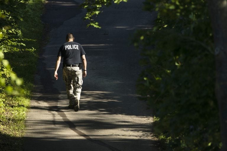 An officer walks up a blocked off drive way, in, Solebury, Pa., as the search continues Wednesday, July 12, 2017, for four missing young Pennsylvania men feared to be the victims of foul play. (AP Photo/Matt Rourke)