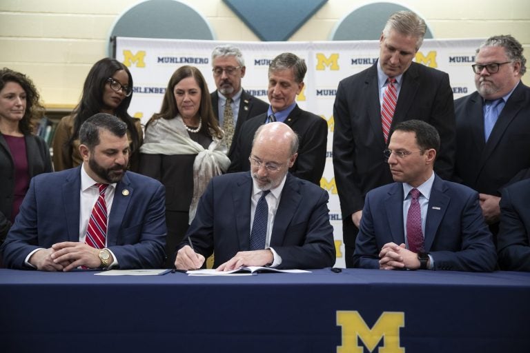 Gov. Tom Wolf, (center), signs legislation into law at Muhlenberg High School in Reading, Pa., Tuesday, Nov. 26, 2019. Wolf approved legislation Tuesday to give future victims of child sexual abuse more time to file lawsuits and to end time limits for police to file criminal charges. (Matt Rourke/AP Photo)