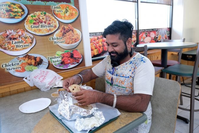 Aman Singh, of Indiana, talks while eating a meal at Eat Spice. (Matt Smith for Keystone Crossroads)