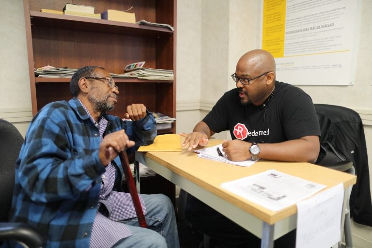 Bill Cobb of Redeemed PA talking with Louis Benson about his right to vote in the Defender Association lobby on Sept. 29, 2016. (David Swanson/The Philadelphia Inquirer) 