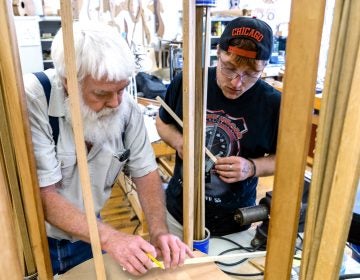 Paul Williams (left) helps Scott Beatty build his 'backpack' guitar. It has a smaller body, meant to easily fit in a pack. Beatty is in the Culture of Recovery program which teaches instrument making to people recovering from addiction. (Caitlin Tan/West Virginia Public Broadcasting)