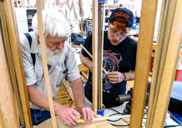 Paul Williams (left) helps Scott Beatty build his ‘backpack’ guitar. It has a smaller body, meant to easily fit in a pack. Beatty is in the Culture of Recovery program which teaches instrument making to people recovering from addiction. Paul Williams (left) helps Scott Beatty build his 'backpack' guitar. It has a smaller body, meant to easily fit in a pack. Beatty is in the Culture of Recovery program which teaches instrument making to people recovering from addiction. (Caitlin Tan/West Virginia Public Broadcasting)