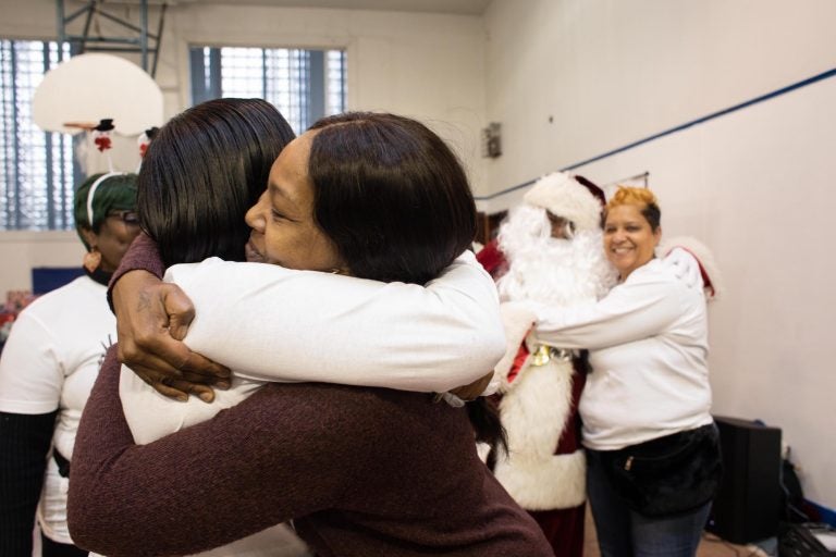 Danielle Shaw (center) embraces a fellow member of Moms Bonded By Grief at a holiday party in South Philadelphia on Dec. 8, 2019. (Becca Haydu for WHYY)