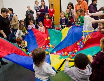 Kids at the Lucien E. Blackwell West Philadelphia Regional Library celebrate “Noon Year’s Eve” by playing with a parachute. (Kimberly Paynter/WHYY)