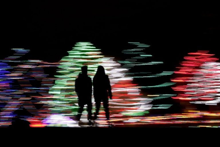 People silhouetted against a Christmas display, at a park in Lenexa, Kan. Most Americans say the holiday season makes them feel very grateful and generous — but many report feeling stressed, too according to a new poll from The Associated Press-NORC Center for Public Affairs Research. (Charlie Riedel/AP Photo)