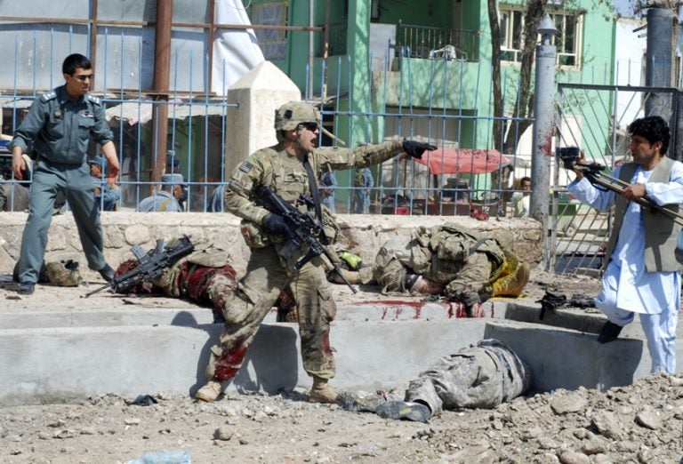 EDS NOTE: GRAPHIC CONTENT - A U.S. soldier shouts at a cameraman at the scene of a suicide attack in Maimanah, the capital of Faryab province north of Kabul, Afghanistan on Wednesday, April 4, 2012. A suicide bomber blew himself up killing at least 10 people, including three NATO service members, officials said, the latest in a string of attacks as spring fighting season gets under way. A senior U.S. defense official has confirmed that two U.S. soldiers were among three NATO forces killed in a suicide bombing in northern Afghanistan. (AP Photo/Gul Buddin Elham)