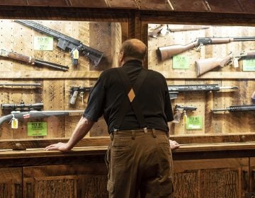 In this April 25, 2019, file photo, a man looks at cases of firearms in the halls of the Indianapolis Convention Center where the National Rifle Association will be holding its 148th annual meeting in Indianapolis. The number of background checks conducted by federal authorities is on pace to break a record by the end of this year. (Lisa Marie Pane/AP Photo)