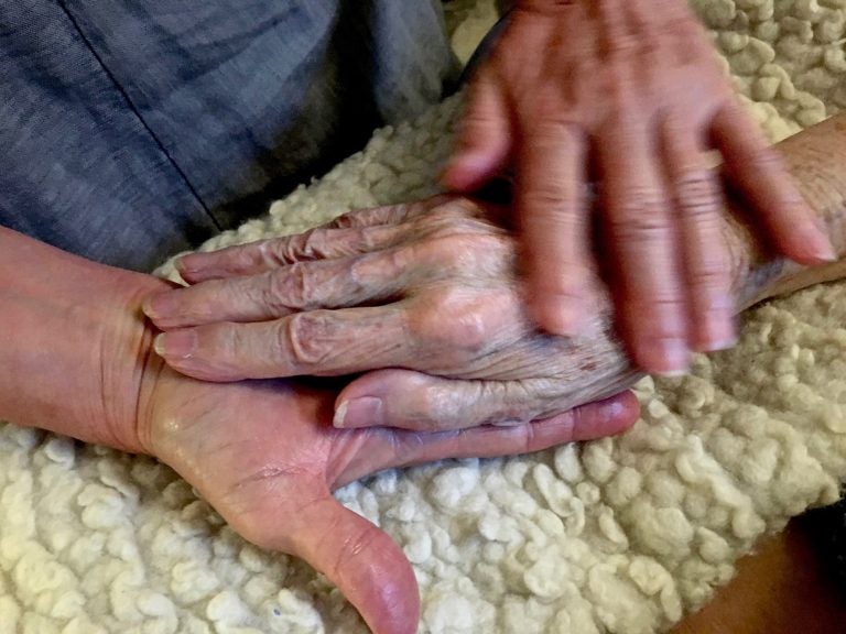 Allison Beach holds the hand of her ailing mother Kathryne Beach inside her home in Hinesburg, Vt. Allison  (Thomas Marrinson/AP Photos)