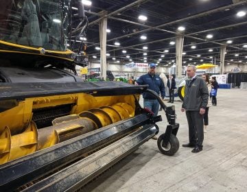 Agriculture Secretary Russell Redding (right) looks at a piece of harvesting equipment with Jason Forrester of Forrester Farm Equipment in Chambersburg, Pa. Redding was giving a tour at the Pennsylvania Farm Show Complex on Monday, December 30, 2019. (Rachel McDevitt/WITF)