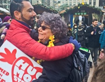 Edie Weinstein gives out hugs at the Christmas Village in Center City. (Annette John-Hall/WHYY)