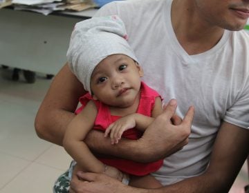 A father in the Philippines holds his child, who was immunized for measles. (Jason Beaubien/NPR)