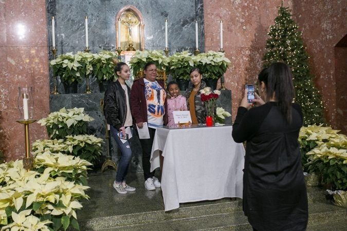 Friends and family of Sincere Howard pose for pictures in front of is his memorial at a vigil at Parish of the Cathedral in Camden, NJ on Monday, December 30, 2019. The 22 hours Vigil was held to commemorate the 24 murders in Camden City in the year 2019. (Miguel Martinez for WHYY).