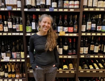 Sande Friedman, the wine buyer at Di Bruno Bros., stands in front of the stock at their Rittenhouse location. (Alex Stern/WHYY)