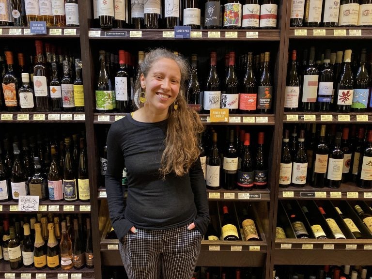 Sande Friedman, the wine buyer at Di Bruno Bros., stands in front of the stock at their Rittenhouse location. (Alex Stern/WHYY)