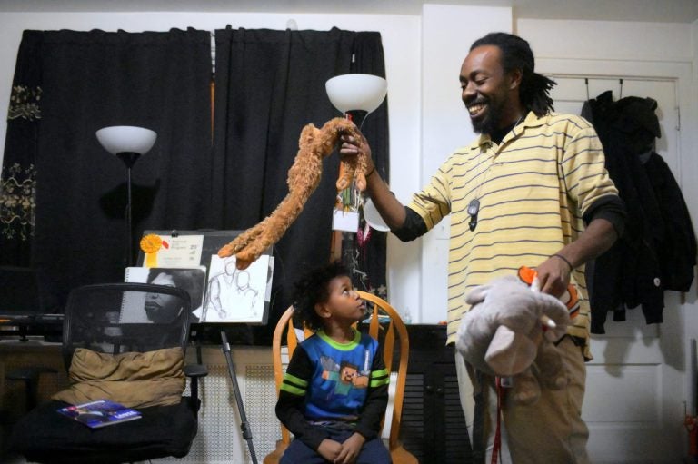 Single parent Deshaun Sherrill and his son Zay’ion Ventura-Sherrill clean up the living room of their home in West Philadelphia. (Bastiaan Slabbers for WHYY)