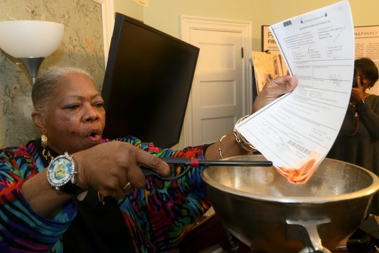 Paul Robeson House Executive Director Vernoca Micheal lights the house's mortgage during a ceremonial burning on Saturday, Jan. 25, 2020. (Bastiaan Slabbers for WHYY)