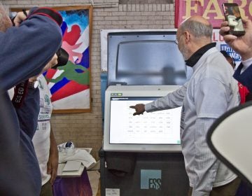 Pa. Gov. Tom Wolf poses with Pennsylvania’s new voting machines at the MLK Day of Service at Philadelphia’s Girard College. (Kimberly Paynter/WHYY)