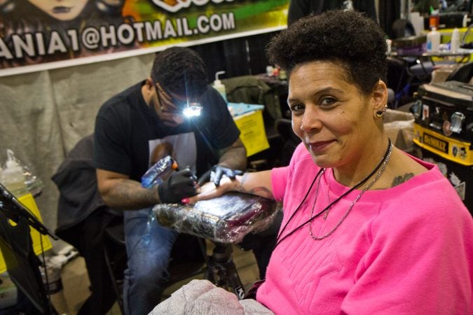 Felicia Vazquez gets a rose tattooed onto her hand by artist Ralph Fryer. (Kimberly Paynter/WHYY)