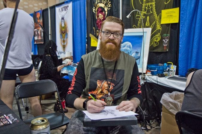 Steven Martin Jr. sketches a tattoo that will be part of his light bulb series. (Kimberly Paynter/WHYY)