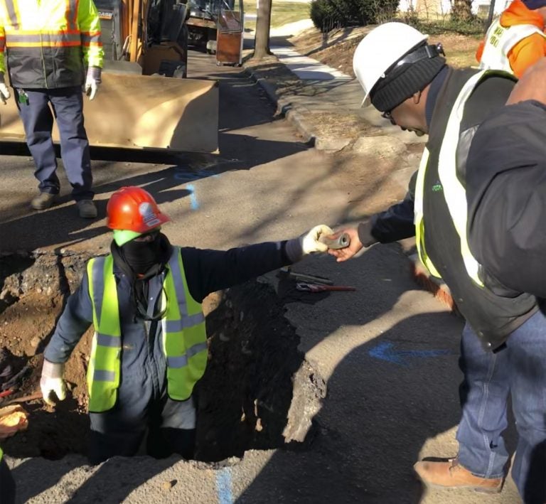 A worker hands a piece of lead pipe to a colleague as they work to remove water service lines Thursday, Jan. 9, 2020, in Trenton, N.J. The city announced it is replacing 37,000 lead pipes over five years as part of an an effort to remove the potentially harmful pipes. (Mike Catalini/AP Photo)