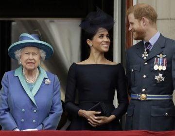 In this Tuesday, July 10, 2018 file photo Britain's Queen Elizabeth II, and Meghan the Duchess of Sussex and Prince Harry watch a flypast of Royal Air Force aircraft pass over Buckingham Palace in London. (Matt Dunham/AP Photo)