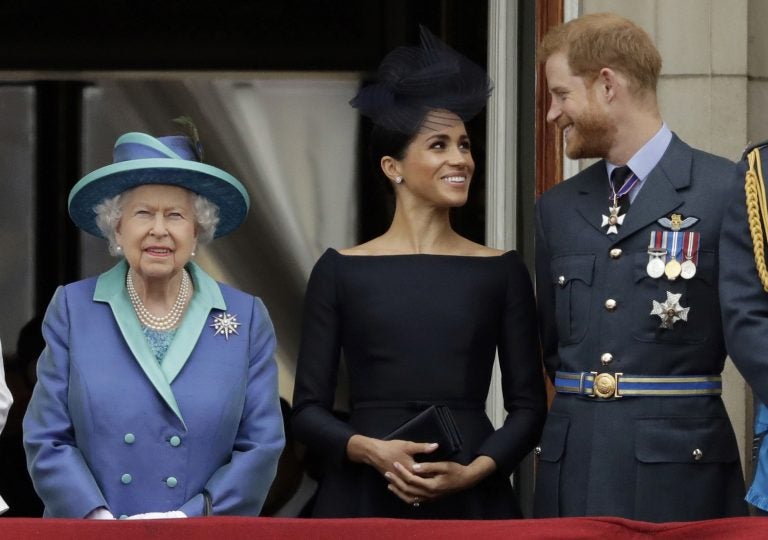 In this Tuesday, July 10, 2018 file photo Britain's Queen Elizabeth II, and Meghan the Duchess of Sussex and Prince Harry watch a flypast of Royal Air Force aircraft pass over Buckingham Palace in London. (Matt Dunham/AP Photo)