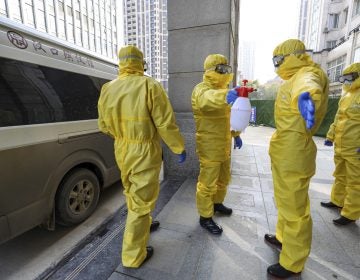 Funeral workers disinfect themselves after handling a virus victim in Wuhan in central China's Hubei Province, Thursday, Jan. 30, 2020. China counted 170 deaths from a new virus Thursday and more countries reported infections, including some spread locally, as foreign evacuees from China's worst-hit region returned home to medical observation and even isolation. (Chinatopix via AP)