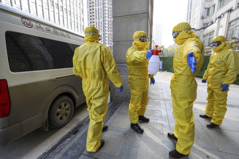 Funeral workers disinfect themselves after handling a virus victim in Wuhan in central China's Hubei Province, Thursday, Jan. 30, 2020. China counted 170 deaths from a new virus Thursday and more countries reported infections, including some spread locally, as foreign evacuees from China's worst-hit region returned home to medical observation and even isolation. (Chinatopix via AP)